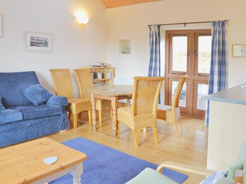 a living room with a blue couch and a table and chairs at The Threshing Barn in Westbury-sub-Mendip