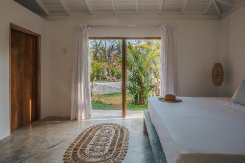 a bedroom with a bed and a large window at Panta Rei resort in Ahangama