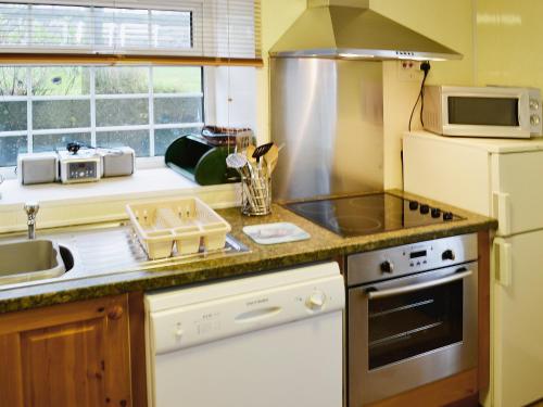 a kitchen with a sink and a stove top oven at Bodwi Bach in Llanengan