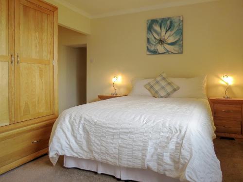 a bedroom with a white bed with two lamps on tables at The Waves in Wick