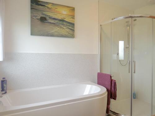 a bathroom with a white tub and a painting on the wall at The Waves in Wick