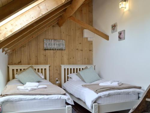 two beds in a room with wooden walls at The Waggon House in Arlingham