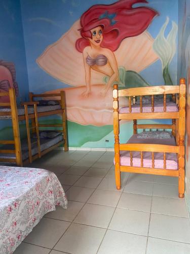a bedroom with a painting of a mermaid on the wall at Colônia Virtual Net in Itanhaém