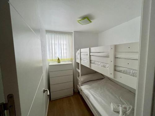 - une petite chambre blanche avec des lits superposés et une fenêtre dans l'établissement Apartamento frente al mar en Calpe con parking para 4 personas, à Calp