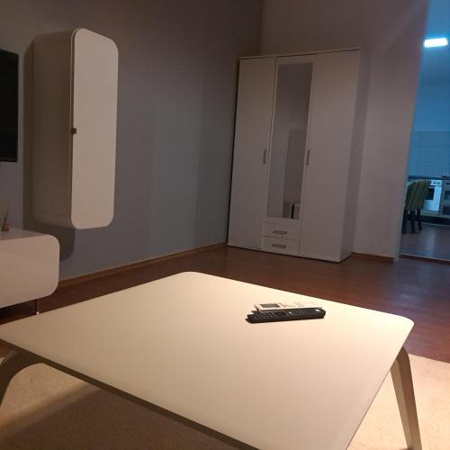 - une télécommande assise sur une table blanche dans le salon dans l'établissement L&M 2 Apartman, à Bijeljina