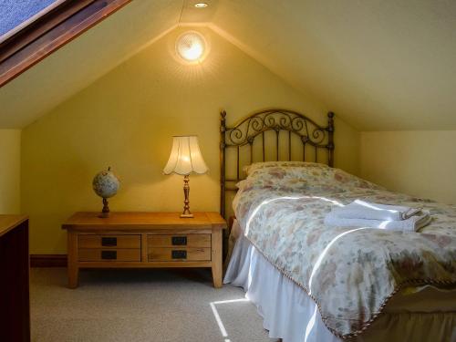 a bedroom with a bed and a lamp on a table at Tan Y Fawnog in Penrhyndeudreath