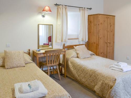 um quarto com 2 camas e uma secretária com um espelho. em The Old Dairy - 26726 em North Willingham