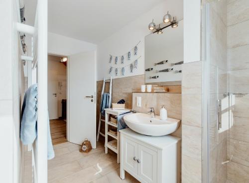 ein weißes Badezimmer mit einem Waschbecken und einem Spiegel in der Unterkunft Ostseeblau in Zingst