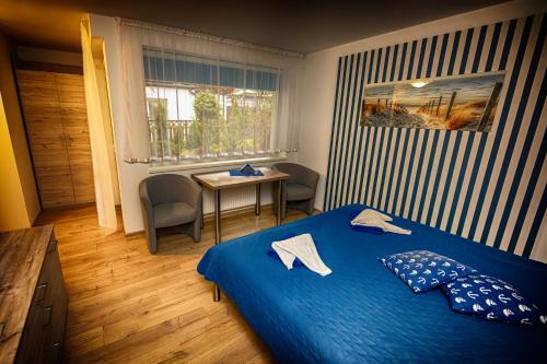sypialnia z niebieskim łóżkiem i stołem w obiekcie Dom Wypoczynkowy Anna w Kołobrzegu