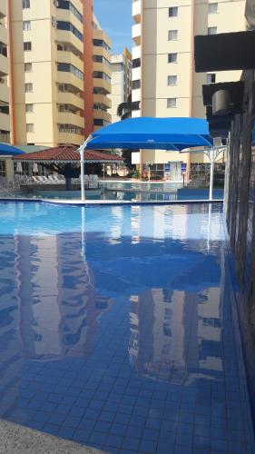 a swimming pool with a blue umbrella and some buildings at Aguas Quentes 601-B in Caldas Novas