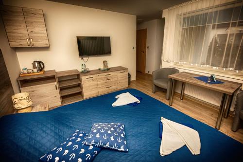 a bedroom with a blue bed and a television at Dom Wypoczynkowy Anna - opcjonalnie śniadania w Starej Piekarni in Kołobrzeg