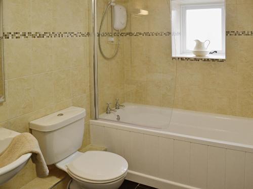 a bathroom with a toilet and a tub and a sink at Meadow Mews in Stokenham