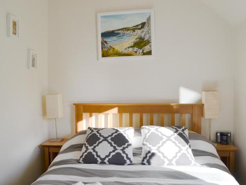 ein Bett mit zwei Kissen und einem Bild an der Wand in der Unterkunft Langside in Kingussie