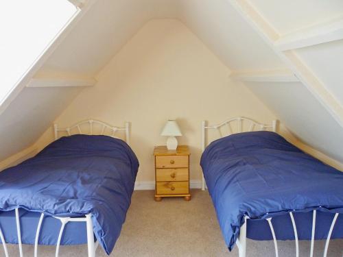 Cette chambre mansardée comprend 2 lits jumeaux et une table de nuit. dans l'établissement Little Boreland, à Gatehouse of Fleet