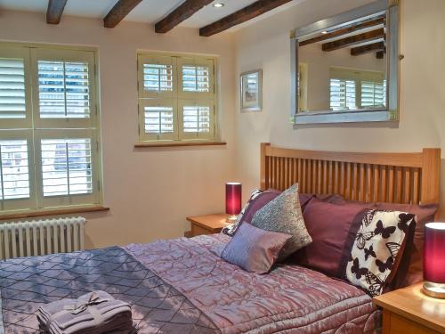 a bedroom with a bed and a mirror and windows at The Hayloft in Stourport