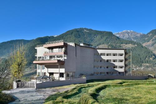 a large building with mountains in the background at juSTa Grand View Resort & Spa, Manali in Manāli
