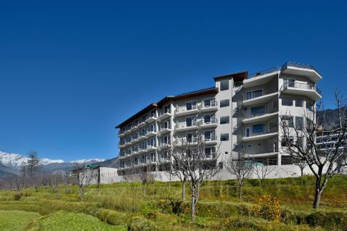 an apartment building on a hill with mountains in the background at juSTa Grand View Resort & Spa, Manali in Manāli