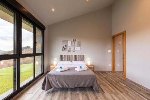 a bedroom with a large bed and large windows at Erretola - Baskey Rentals in Aizarnazábal