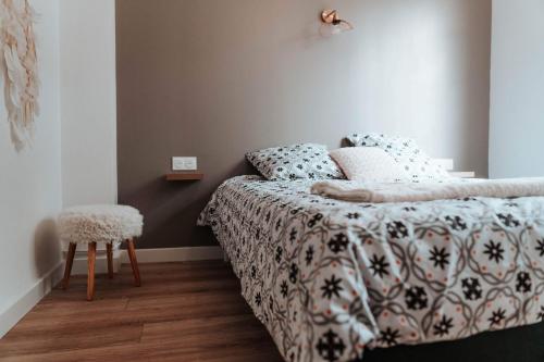a bedroom with a bed with a comforter and a stool at Le petit rempart - Appt lumineux 2pers au coeur de Blois in Blois