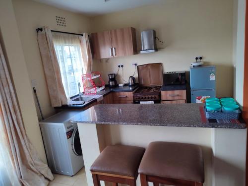 a kitchen with a counter with stools in it at Nests by Too in Eldoret