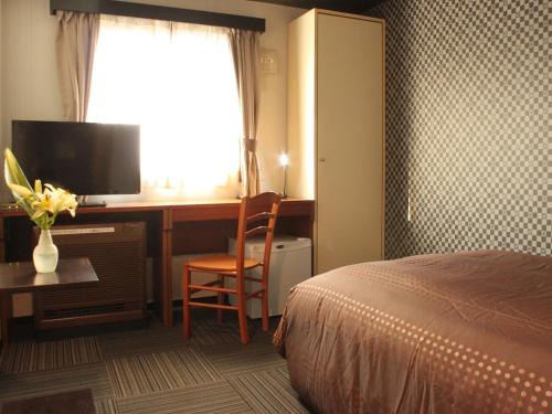 Habitación de hotel con cama y escritorio con TV. en HOTEL LiVEMAX BUDGET Tokyo Hamura Ekimae en Hamura