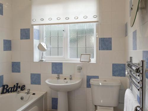 a bathroom with a sink and a toilet and a window at The Glade in Ferring
