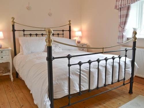 a bedroom with a black and white bed with white sheets at Sweet Pea Cottage in Heacham
