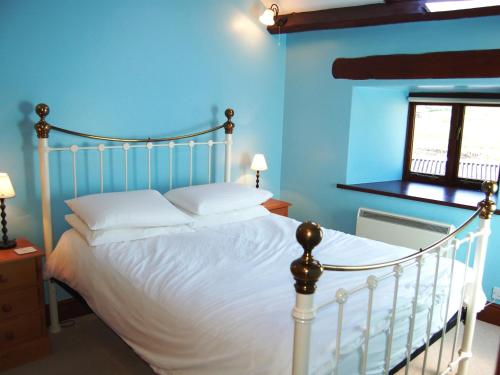 a bedroom with a white bed with a blue wall at Gill Barn in Bampton