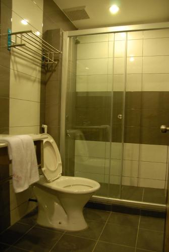 a bathroom with a toilet and a glass shower at Queen Hotel in Keningau