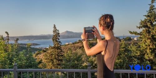 a woman taking a picture of the ocean at Villa YOLO in Almirida