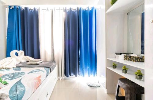 Grass Residences SM North Edsa and Trinoma في مانيلا: غرفة نوم مع ستائر زرقاء وسرير في غرفة