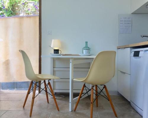 - deux chaises assises à côté d'une table dans la cuisine dans l'établissement Appart Bianca T2 - Terrasse - Parking - Calme - 1mn de la mer, à Cassis