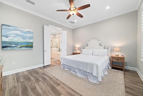 a white bedroom with a bed and a ceiling fan at Starfish Cottage in Gulf Shores