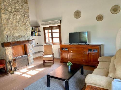 a living room with a couch and a tv and a fireplace at Casona La Teja en Ribadedeva in Noriega