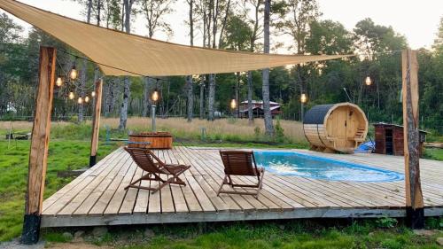 une terrasse en bois avec deux chaises et une piscine dans l'établissement route 199 cabaña exclusiva centro de eventos, à Pucón