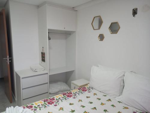a small bedroom with a bed and a white wall at Apartamento Encantador - MAKAMBIRA RESIDENCE in Porto De Galinhas