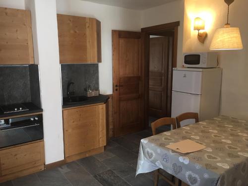 a kitchen with a table and a white refrigerator at Appartamento Montagnards in Morgex