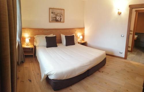 a bedroom with a large white bed with two tables at Appartamento Montagnards in Morgex
