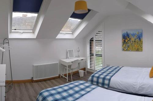 a bedroom with two beds and a desk and two windows at Cosy 2 Bedroom Coach House in Belfast