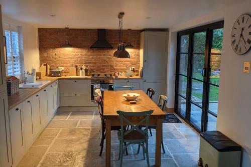 a kitchen with a wooden table and a clock on the wall at Cosy 2 Bedroom Coach House in Belfast