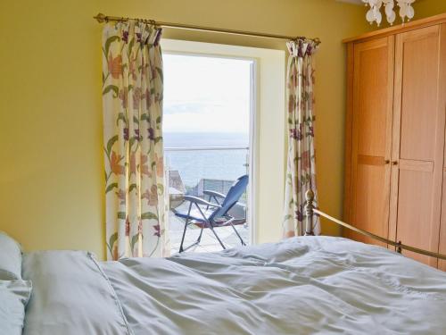 a bedroom with a bed and a window with a view of the ocean at Buckingham Cottage in Ventnor