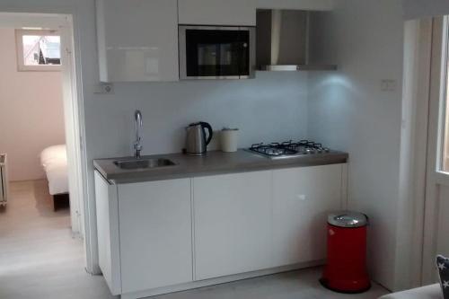 a kitchen with a counter with a sink and a stove at Modern en sfeervol appartement aan zee met airco in Zoutelande