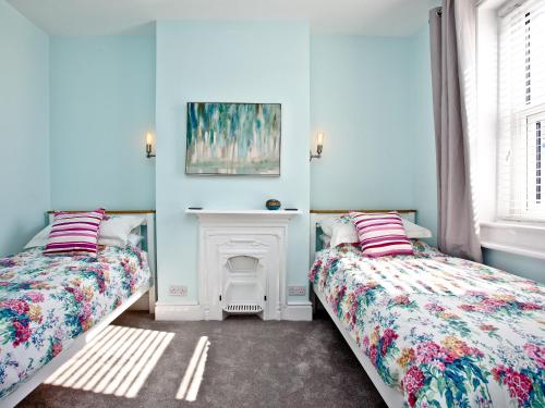 a blue room with two beds and a fireplace at Cornerstone in Castletown