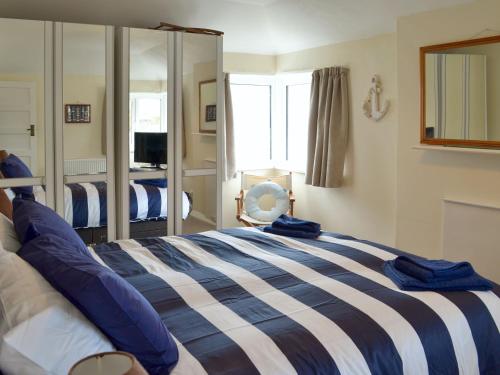 a bedroom with a blue and white bed with a mirror at Rosehill in Goodrington