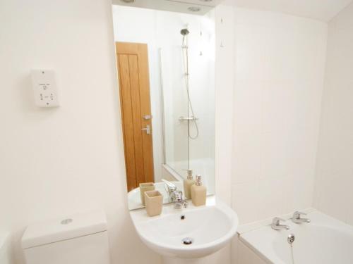 a white bathroom with a sink and a toilet at Dandelion Cottage - 28151 in Totnes