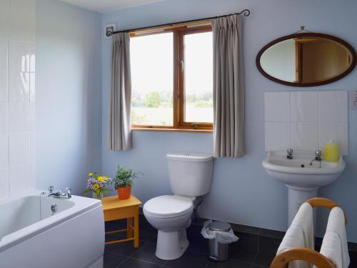 a bathroom with a toilet and a tub and a sink at The Old Calf House in Little Baddow