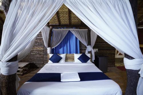 a bedroom with a bed with blue and white curtains at Farm Stay Resort - Shamirpet, Hyderabad in Hyderabad