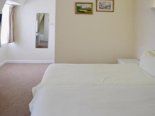uma cama branca num quarto com um espelho em Trinity em St Brelade