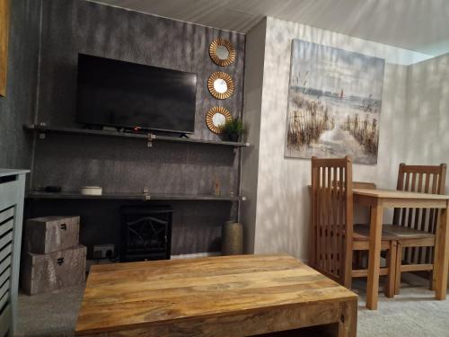 een woonkamer met een open haard en een tv aan de muur bij Penbryn Holidays No 2 in Barmouth