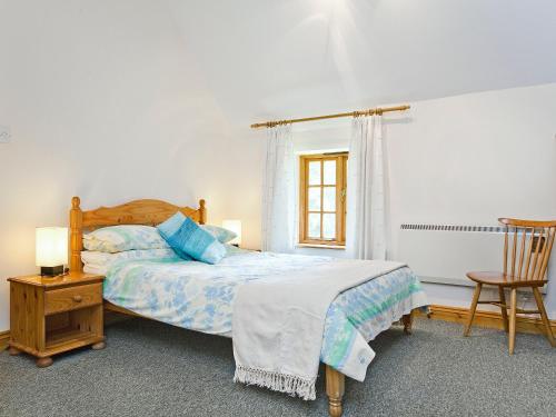 a bedroom with a bed and a chair at Thatch Cottage in Saint Hilary
